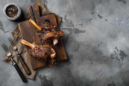 Baked lamb shank with barley and ale set, on gray stone table background, top view flat lay, with copy space for text