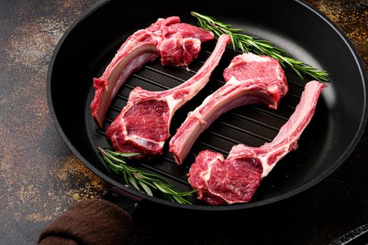 Lamb chops raw meat on bone set, on frying cast iron pan, on old dark rustic table background