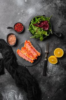 Fresh frozen organic crab legs set, on black dark stone table background, top view flat lay, with copy space for text