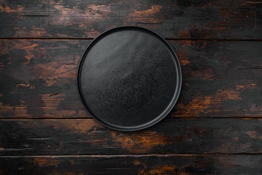 Black plate set, on old dark wooden table background