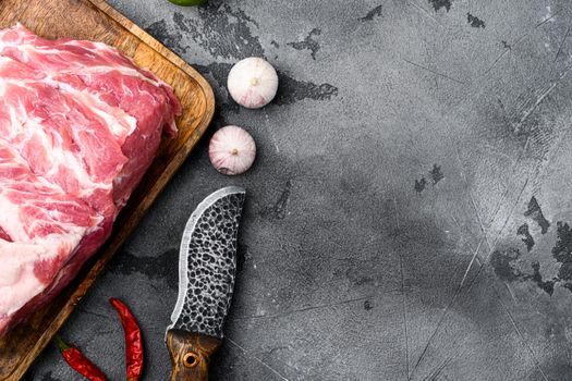 Piece of fresh raw pork from the neck set, with ingredients and herbs, on gray stone table background, top view flat lay, with copy space for text