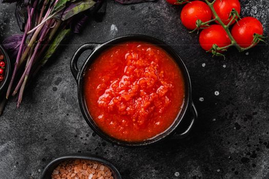 Tomato sauce in small bowl set, on black dark stone table background, top view flat lay