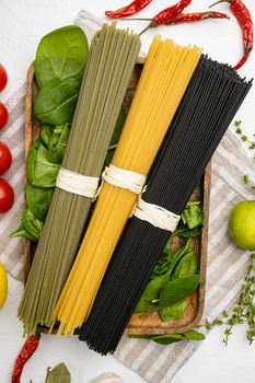 Multi colored spaghetti with ingredients set, on white stone table background, top view flat lay