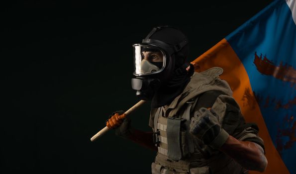 a male soldier in military uniform in a bloody gas mask holds a bloodstained flag of Russia on a black background