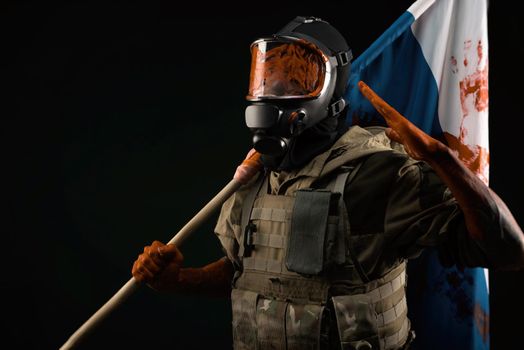 a male soldier in military uniform in a bloody gas mask holds a bloodstained flag of Russia on a black background