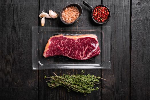 Vacuum packed beef set, on black wooden table background, top view flat lay, with copy space for text