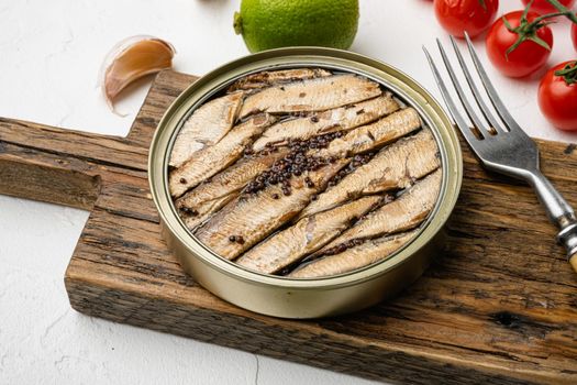 Baltic canned seafood fish sprats in a tin can with oil set, on white stone table background