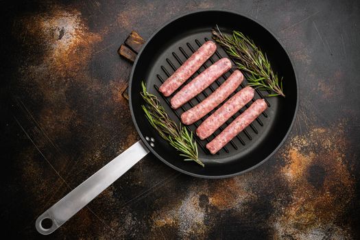 Raw sausage for frying set, on frying cast iron pan, on old dark rustic table background, top view flat lay, with copy space for text