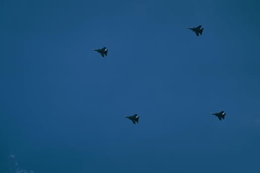 Victory parade of military aircraft over the city. Representation of aviation equipment. Group of army air force shows aerobatics in blue sky.