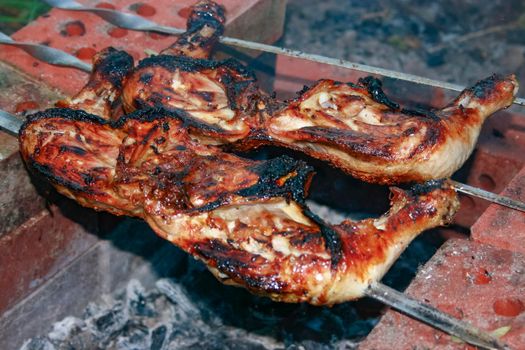 Roast chicken on a bonfire close-up on a spit.