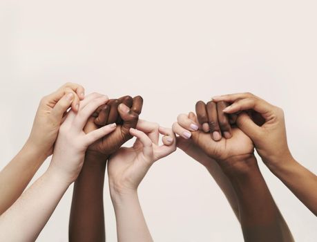 Cropped shot of a group of hands reaching up and holding on to each other.