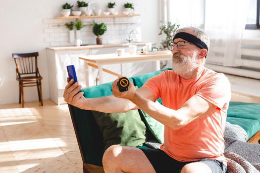 Senior man doing fitness exercise at home with dumbbells - elderly people and wellness health
