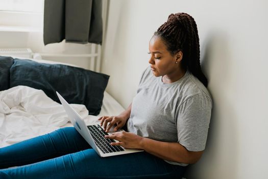 African american young woman using laptop on bed - technologies and communication and social network