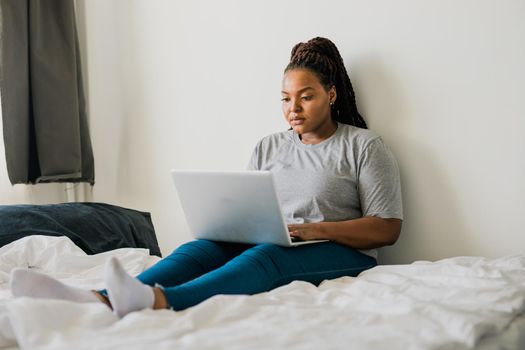 African american young woman using laptop on bed - technologies and communication and social network