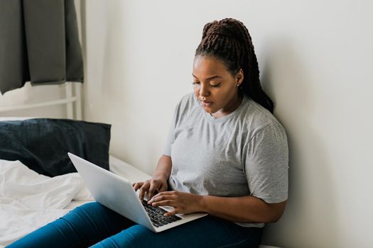 African american young woman using laptop on bed - technologies and communication and social network