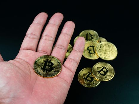 bitcoin coin placed on the hand on a black background
