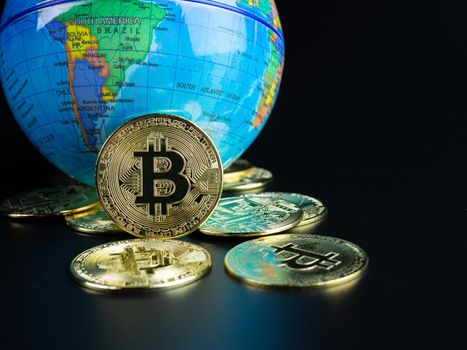 Bitcoin Coins Placed Ahead of a Model World on a black background