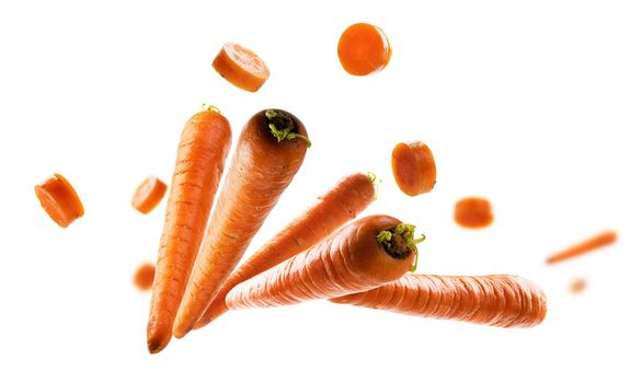 Ripe carrots whole and sliced levitate on a white background.
