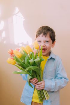 A boy with a bouquet of tulips lifestyle . Postcard for March 8. Congratulations on Women's Day. Congratulations on Mother's Day. Flowers are tulips. Baby and flowers