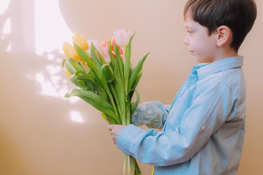 A boy with a bouquet of tulips lifestyle . Postcard for March 8. Congratulations on Women's Day. Congratulations on Mother's Day. Flowers are tulips. Baby and flowers