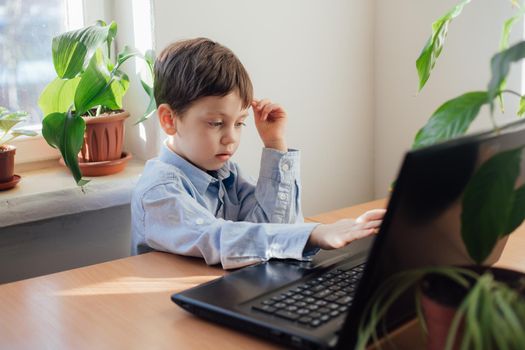 The boy is engaged in online education . Online training. Home schooling. A laptop. Child and technology. An article about the choice of education for a child. Article about home schooling online