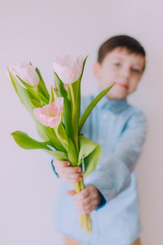 A boy with a bouquet of tulips lifestyle . Postcard for March 8. Congratulations on Women's Day. Congratulations on Mother's Day. Flowers are tulips. Baby and flowers