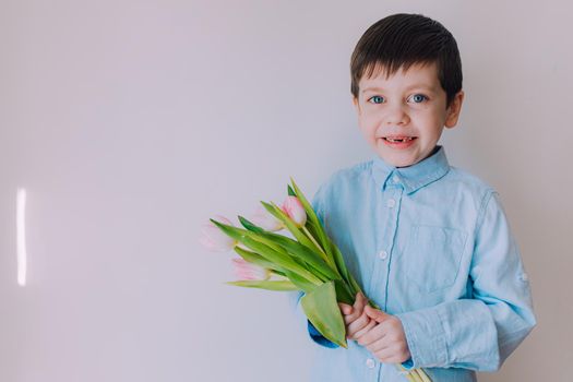 A boy with a bouquet of tulips lifestyle . Postcard for March 8. Congratulations on Women's Day. Congratulations on Mother's Day. Flowers are tulips. Baby and flowers