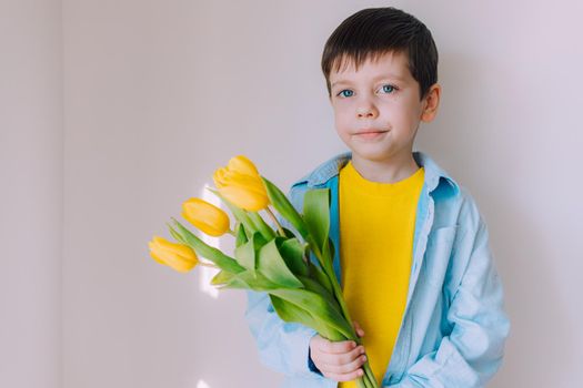 A boy with a bouquet of tulips lifestyle . Postcard for March 8. Congratulations on Women's Day. Congratulations on Mother's Day. Flowers are tulips. Baby and flowers