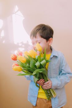 A boy with a bouquet of tulips lifestyle . Postcard for March 8. Congratulations on Women's Day. Congratulations on Mother's Day. Flowers are tulips. Baby and flowers