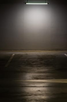 Empty parking lot with overhead dim light, underground parking garage.