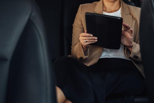 Unrecognisable Female Entrepreneur Working on Tablet While Sitting on Back Seat of Car