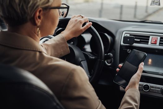 Business Woman Using Smartphone While Driving Car, View from Back Seat