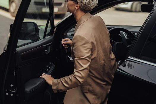 Woman Dressed in Rumpled Brown Jacket Getting from the Car