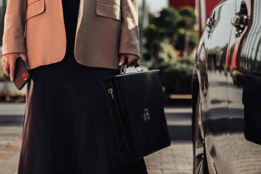 Unrecognisable Elegant Business Woman with Briefcase and Smartphone Standing Near the Car