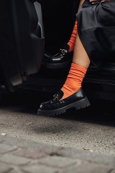 Unrecognisable Stylish Woman in Fashionable Shoes and Orange Socks Getting Out from Car