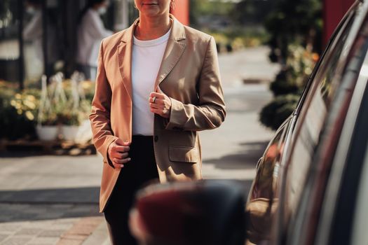 Unrecognisable Stylish Woman in Brown Jacket Moving Near Car
