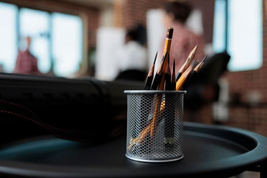 Close up of graphic pencils stand standing on table in creativity school studio. In background diverse team drawing vase sketch on canvas working at sketching technique. New years resolutions