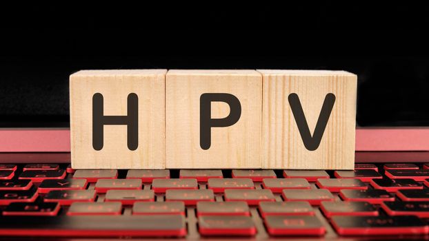 HPV the inscription on wooden cubes on the illuminated laptop keyboard.