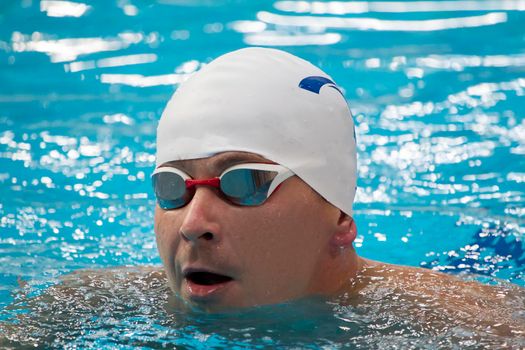 Close-up portrait of a swimmer in swimming goggles and a hat.
