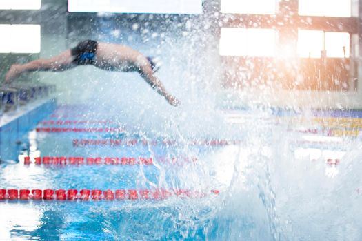 Blurred man is not an athlete dives in the pool into the water.