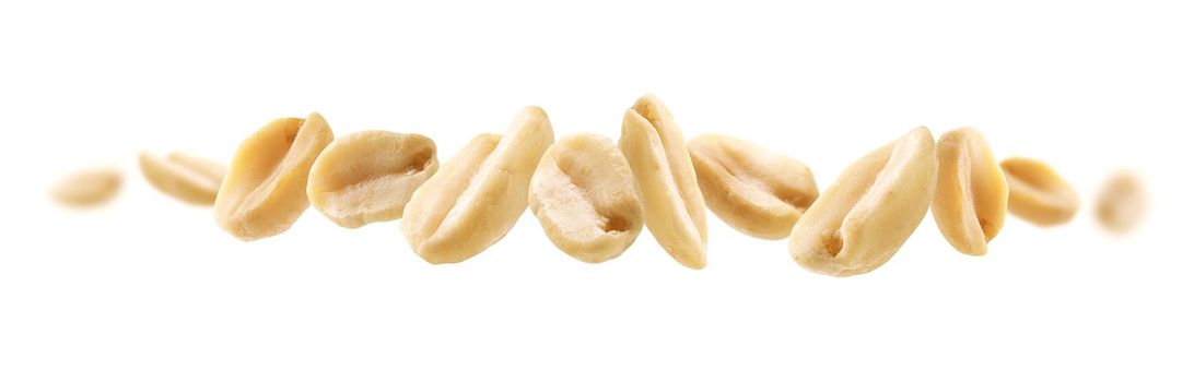 Peeled peanuts levitate on a white background.