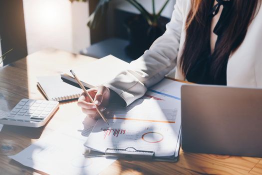 Young economists or accountants or financiers and investors are reviewing budget documents and using computers to study impact and risk assessments on corporate investment management