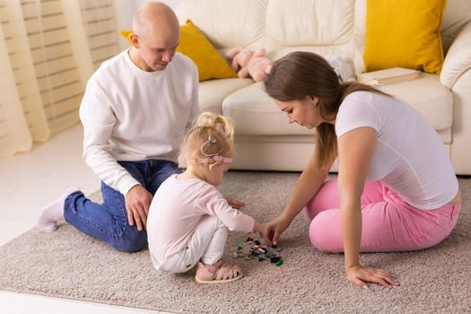 Baby child with hearing aids and cochlear implants plays with parents on floor. Deaf and rehabilitation