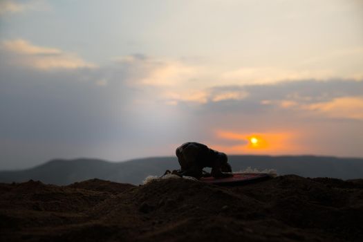 Silhouette of muslim prayer on sunset. Ramadan Kareem background. Praying people. Selective focus