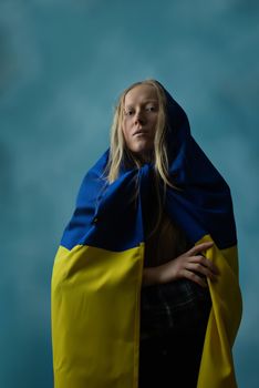 A real Ukrainian blonde during the war with the state yellow and blue Ukrainian flag on her head like a handkerchief. Russia attacked Ukraine on February 24, 2022.