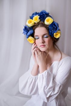 Beautiful Ukrainian woman in a white and floral wreath. Symbol of the Ukrainian yellow blue flag. The calm lady is asleep. Peace in Ukraine