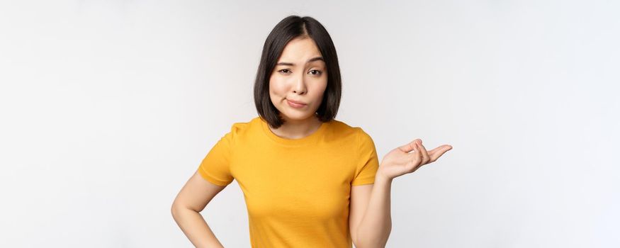 So what. Unbothered asian woman shrugging, looking clueless, standing against white background. Copy space
