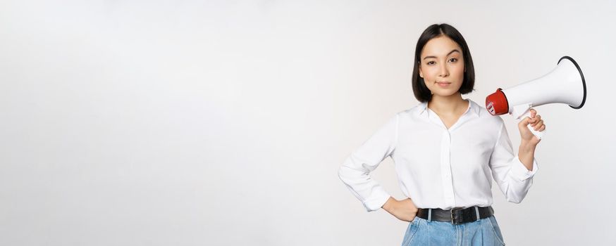 Image of modern asian woman with megaphone, making announcement, white background.