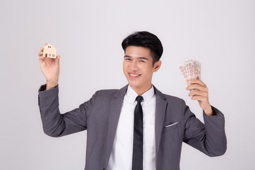 Young asian business man holding home and money Thai for planning saving future, insurance agent and credit, debt and loan of finance, purchase home and refinance, investment about real property.