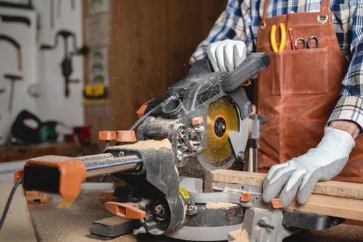 Carpenter using an electric circular saw, cutting piece of wood. High quality photo.